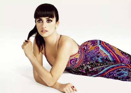A stunning HD desktop wallpaper featuring Penelope Cruz, elegantly posed in a vibrant, patterned dress, exuding grace and beauty against a clean, minimal background.