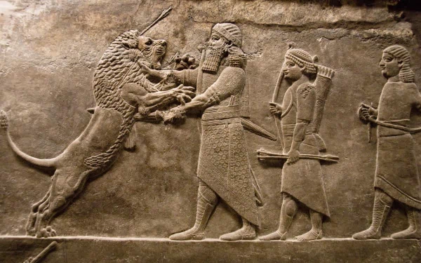 Artistic HD PC desktop wallpaper depicting an ancient Assyrian lion hunt carved in detailed stone relief.