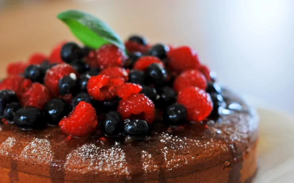 Close-up of a chocolate cake topped with fresh raspberries and blueberries, captured in 4K Ultra HD for a vibrant PC desktop wallpaper background.