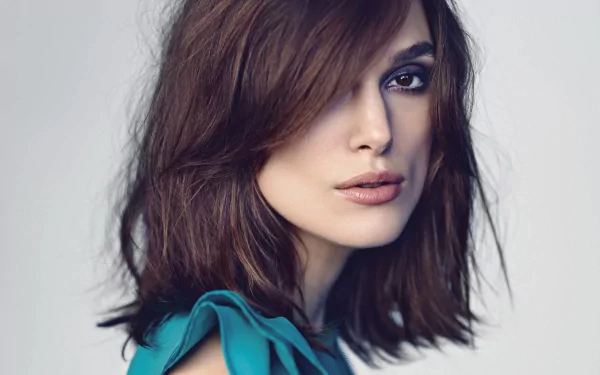 A striking HD wallpaper featuring English actress Keira Knightley, showcasing her brown eyes and brunette hair, captured in a captivating pose.