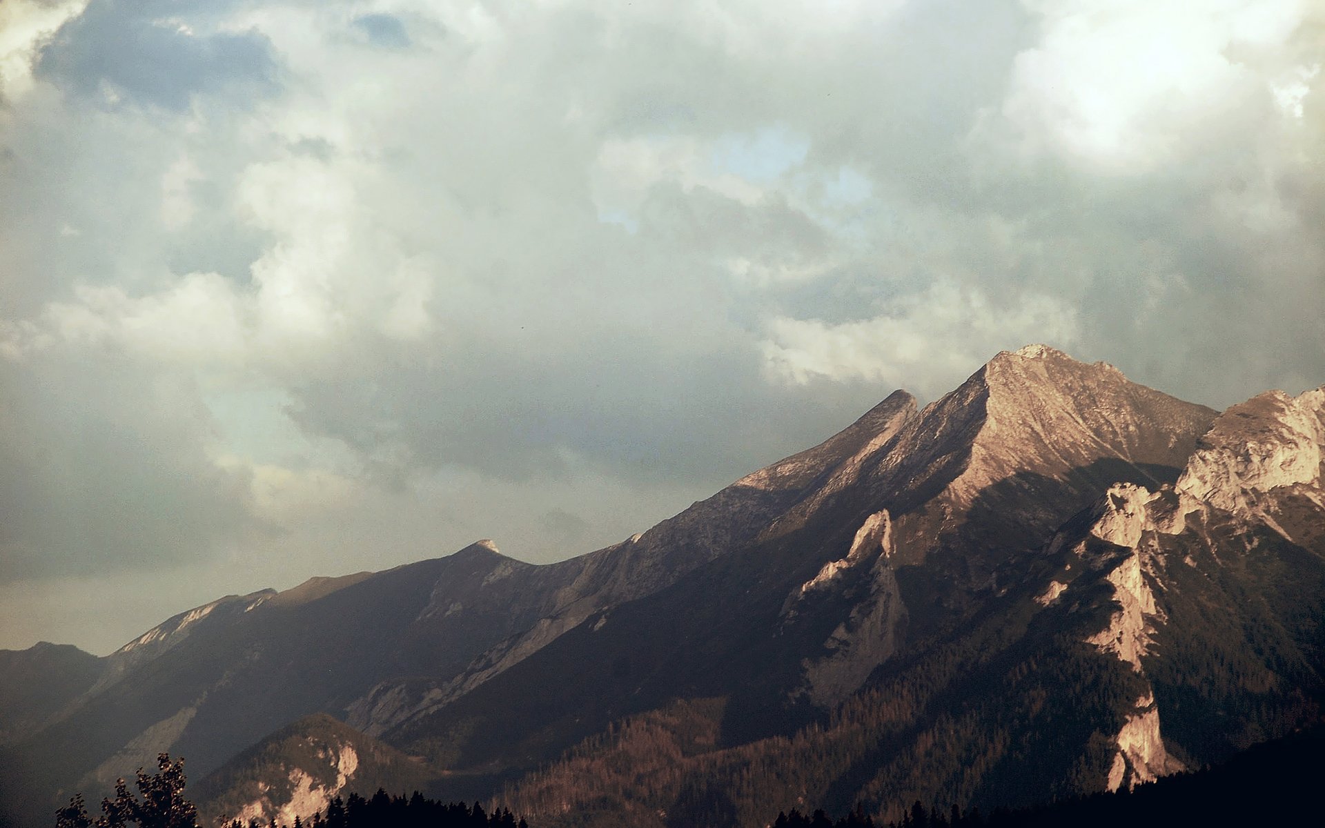 HD desktop wallpaper featuring a majestic mountain range under a cloudy sky, showcasing the beauty of nature in stunning detail.