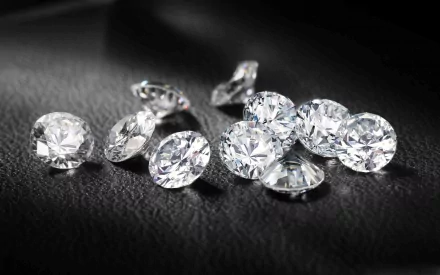 A collection of sparkling, man-made diamonds scattered on a dark background, creating an elegant HD wallpaper for desktop use.