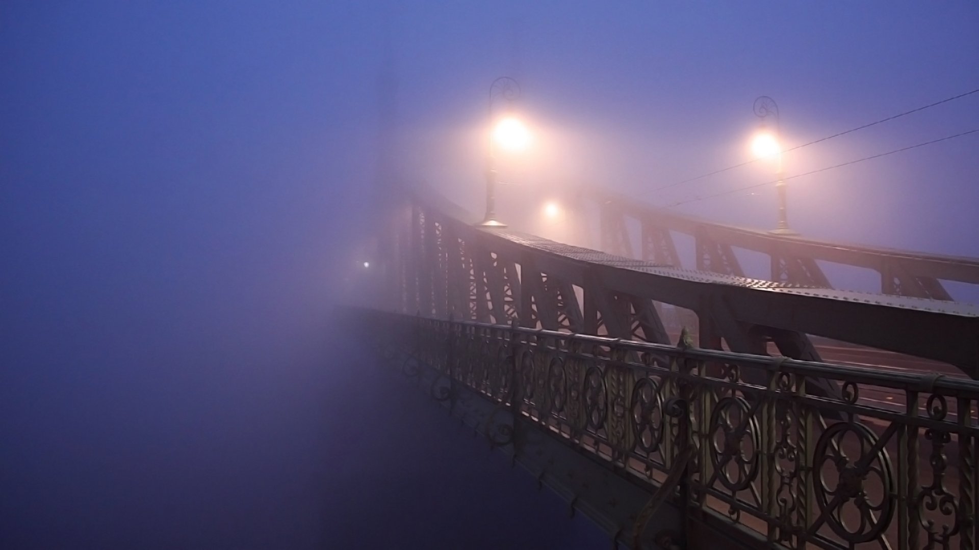 A foggy scene captures a man-made bridge illuminated by soft lights, creating an atmospheric and serene backdrop for a stunning HD desktop wallpaper.