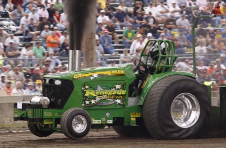 John Deere 8530 green tractor vehicle with oversized rear tires and smoke at a packed motorsport event — 2K Quad HD PC desktop wallpaper/background.