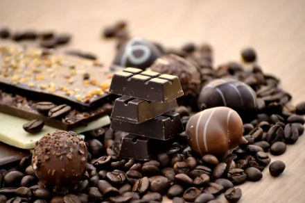 A tantalizing array of chocolates and chocolate bars surrounded by coffee beans, creating a rich and inviting backdrop for this HD desktop wallpaper.