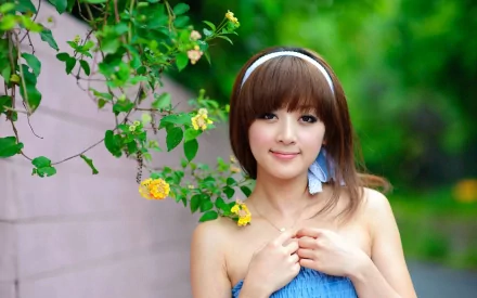 A woman named Mikako Zhang Kaijie poses against a vibrant green backdrop, adorned with blooming flowers, creating a serene and colorful HD desktop wallpaper.