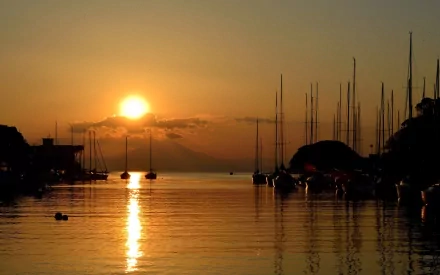 HD PC desktop wallpaper: man-made harbor at sunset, silhouetted masts and moored boats reflecting on calm water beneath a golden sky.