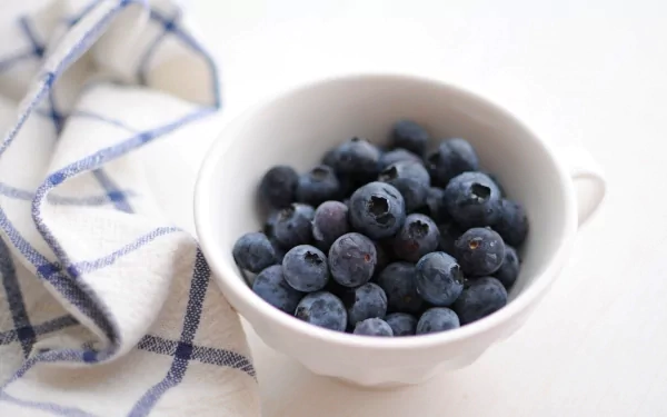 Close-up of fresh blueberries in a white cup on a checkered cloth, captured in 4K Ultra HD for a vibrant PC desktop wallpaper and background.
