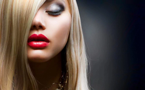 A stunning HD desktop wallpaper featuring a woman with striking long hair, bold red lips, and smoky eye makeup, set against a dark, elegant background.