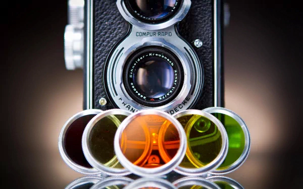 A high-definition desktop wallpaper featuring a vintage camera with colorful filters in the foreground, highlighting the artistry of photography and its tools.
