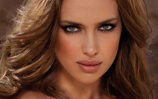 A stunning HD wallpaper featuring celebrity Irina Shayk, showcasing her striking features and captivating gaze against a warm, blurred background.
