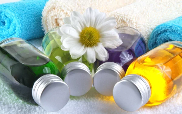 HD desktop wallpaper featuring a man-made spa scene with colorful essential oil bottles, white daisy, and rolled towels in the background.