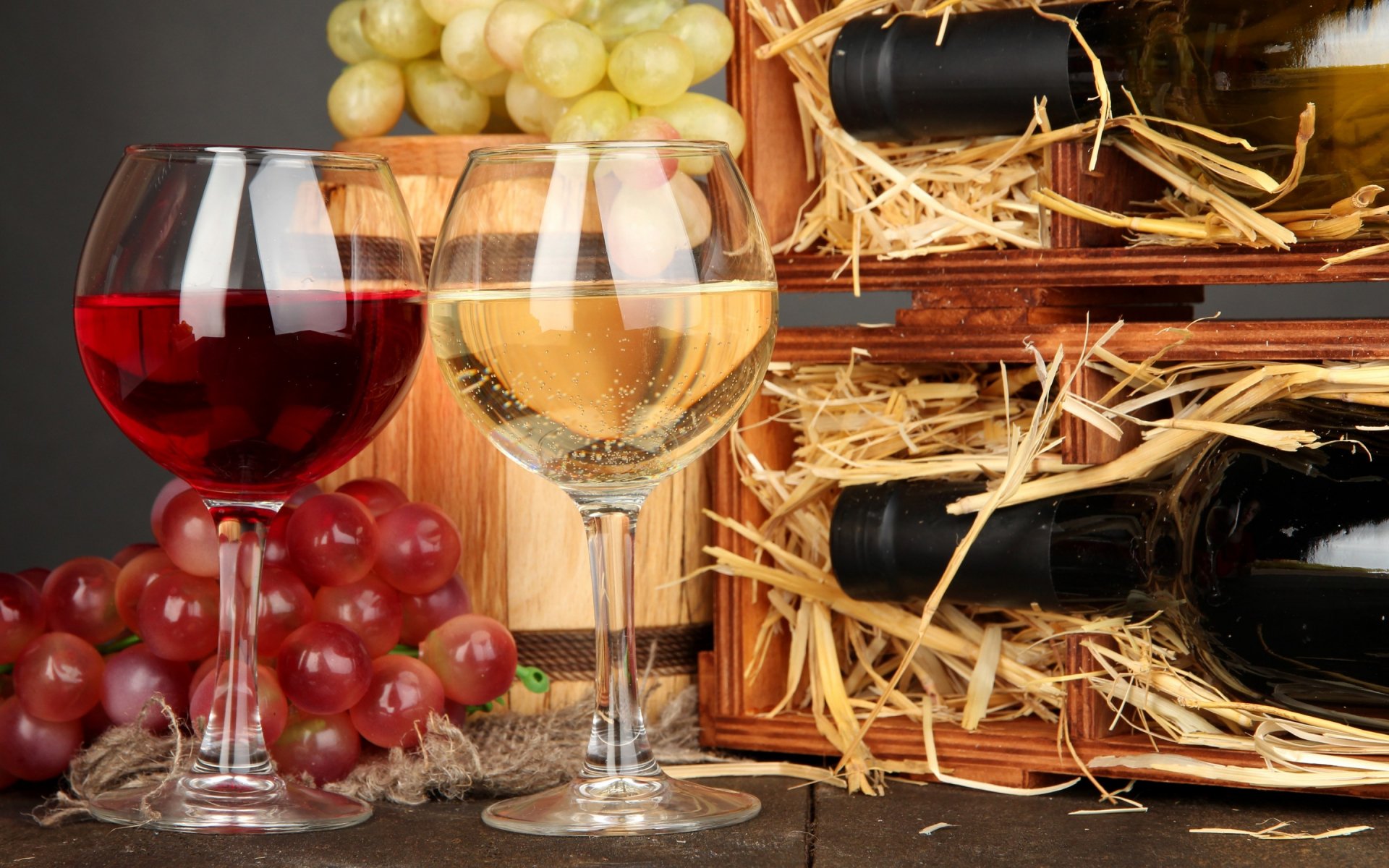 Elegant HD wallpaper showcasing two glasses of red and white wine, surrounded by fresh grapes and wooden wine crates, creating a warm food and wine ambiance.