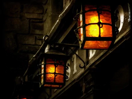 A close-up of two glowing lanterns, showcasing intricate metalwork and warm amber light. This HD wallpaper offers a captivating man-made aesthetic for desktop backgrounds.
