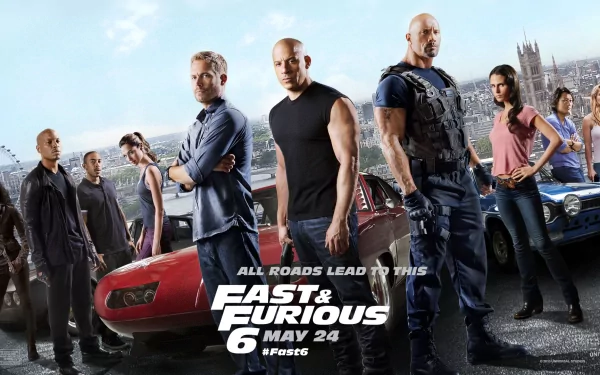 HD desktop wallpaper of the movie Fast & Furious 6, featuring the main cast posing in front of cars with a cityscape in the background. Text reads All roads lead to this and Fast & Furious 6 - May 24.