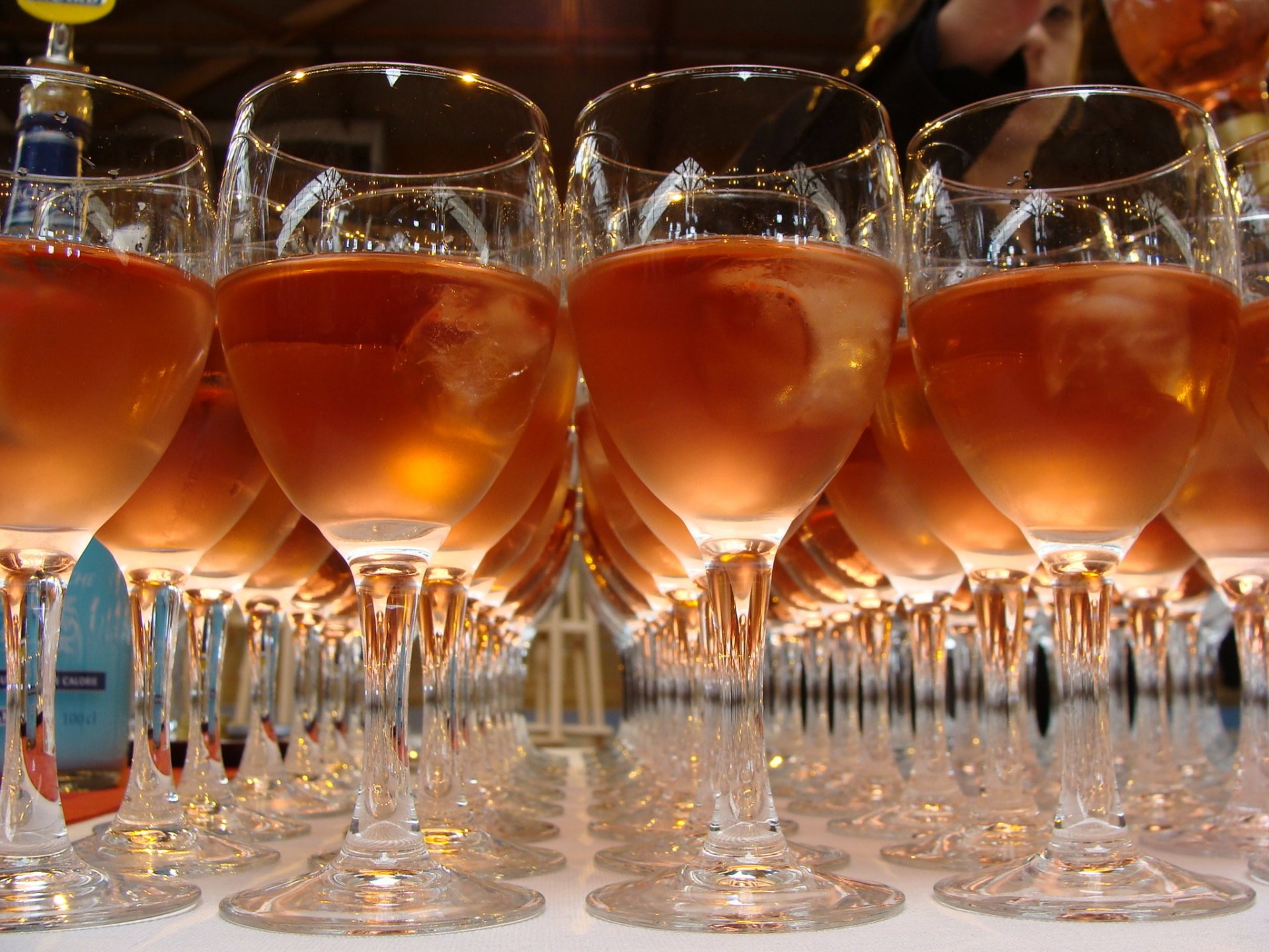 HD desktop wallpaper featuring rows of wine glasses filled with rose-colored wine, reflecting warm light and creating a visually striking food and wine theme.