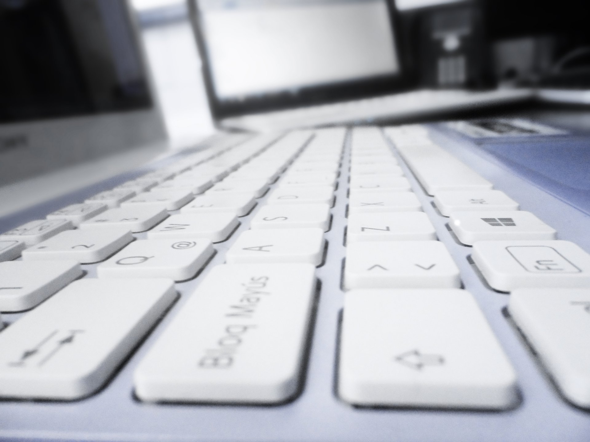 Close-up view of a sleek white keyboard, showcasing modern technology, set against a blurred background of a PC desktop. A 4K Ultra HD wallpaper with a clean, minimal aesthetic.