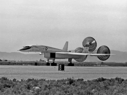 Black-and-white 2K Quad HD PC desktop background of a military North American XB-70 Valkyrie landing on a desert runway with its drag parachutes deployed.