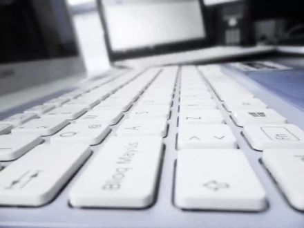 Close-up view of a sleek white keyboard, showcasing modern technology, set against a blurred background of a PC desktop. A 4K Ultra HD wallpaper with a clean, minimal aesthetic.