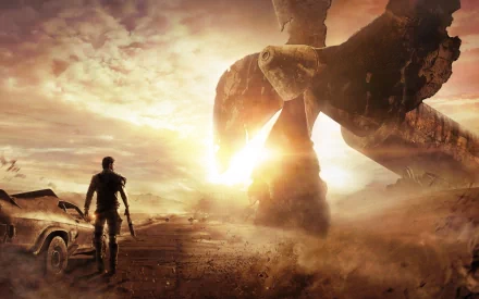 A man stands in a desolate landscape from the video game Mad Max, gazing at a massive turbine against a dramatic sunset, evoking the game's post-apocalyptic themes. HD desktop wallpaper.