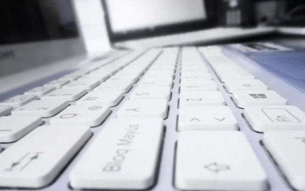Close-up view of a sleek white keyboard, showcasing modern technology, set against a blurred background of a PC desktop. A 4K Ultra HD wallpaper with a clean, minimal aesthetic.