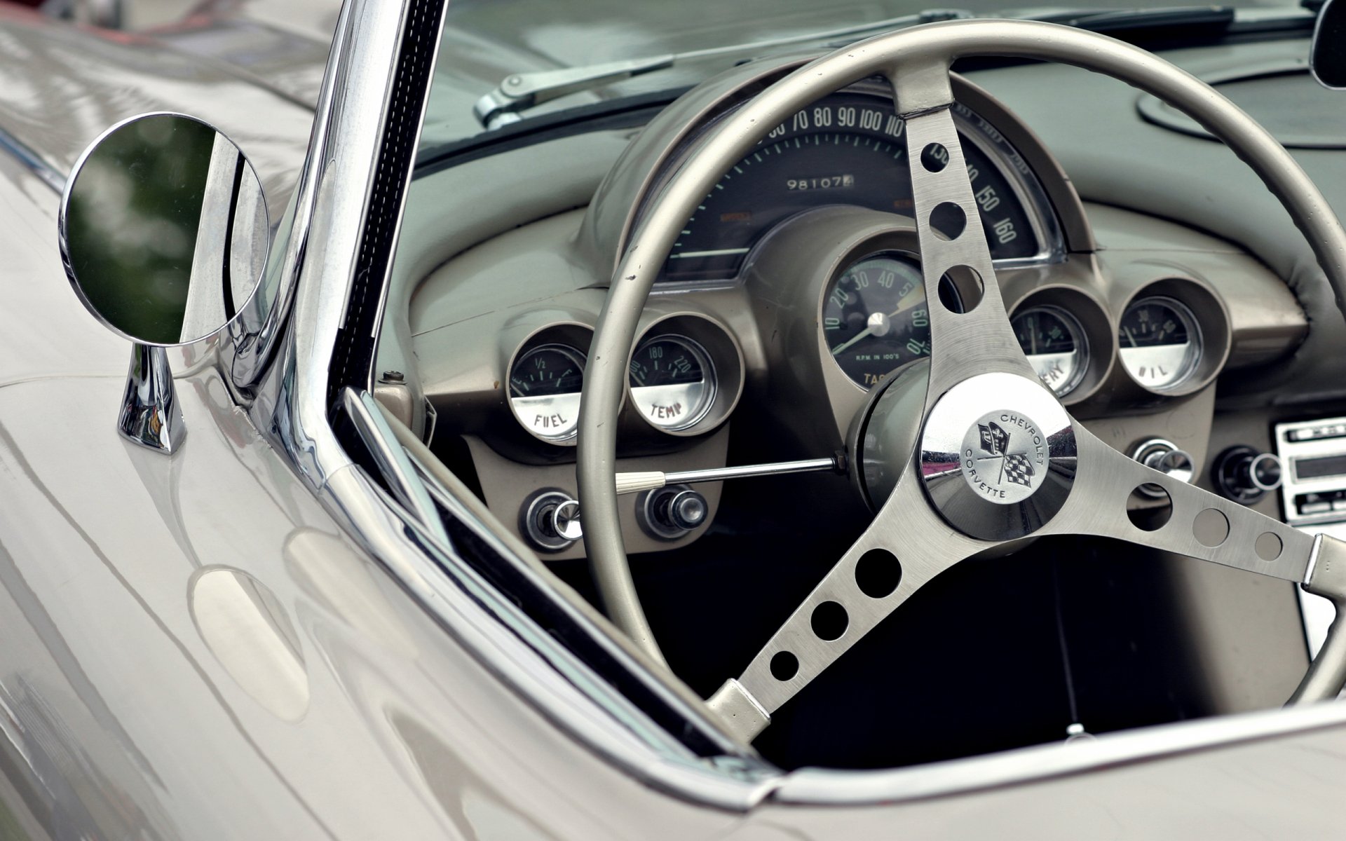 Close-up of a classic Chevrolet vehicle’s steering wheel and dashboard in a glossy silver coupe — 2K Quad HD PC Desktop Wallpaper and Background