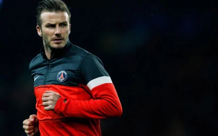 Image of David Beckham in a sports setting, dressed in a red and black athletic jacket. This HD desktop wallpaper captures the iconic athlete in action.