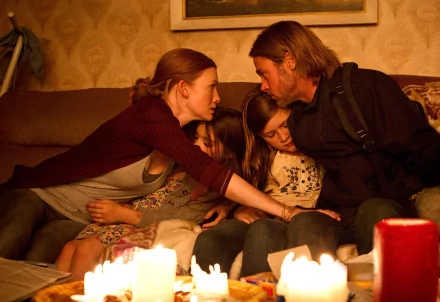 HD PC desktop wallpaper from the movie World War Z showing a family huddled closely together on a couch, illuminated by candlelight.