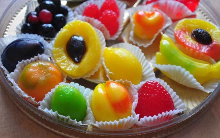HD PC desktop wallpaper featuring an assortment of colorful, fruit-shaped candy arranged on a clear platter, highlighting vibrant textures and glossy finishes.