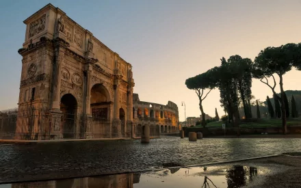 The image captures the grandeur of the Arch of Constantine beside the Colosseum in Rome, showcasing stunning architecture and ruins under a soft sunset glow.