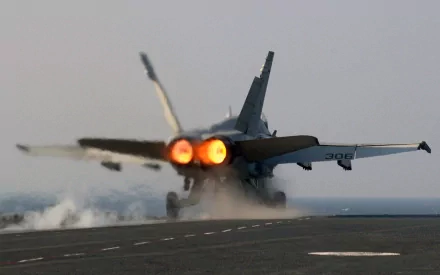 A McDonnell Douglas F/A-18 Hornet fighter jet takes off from an aircraft carrier, captured in HD as a dynamic military desktop wallpaper.