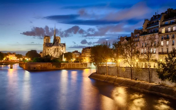 A stunning HD wallpaper featuring Notre-Dame de Paris at dusk, illuminated along the Seine, highlighting the beauty of this iconic religious landmark in Paris.
