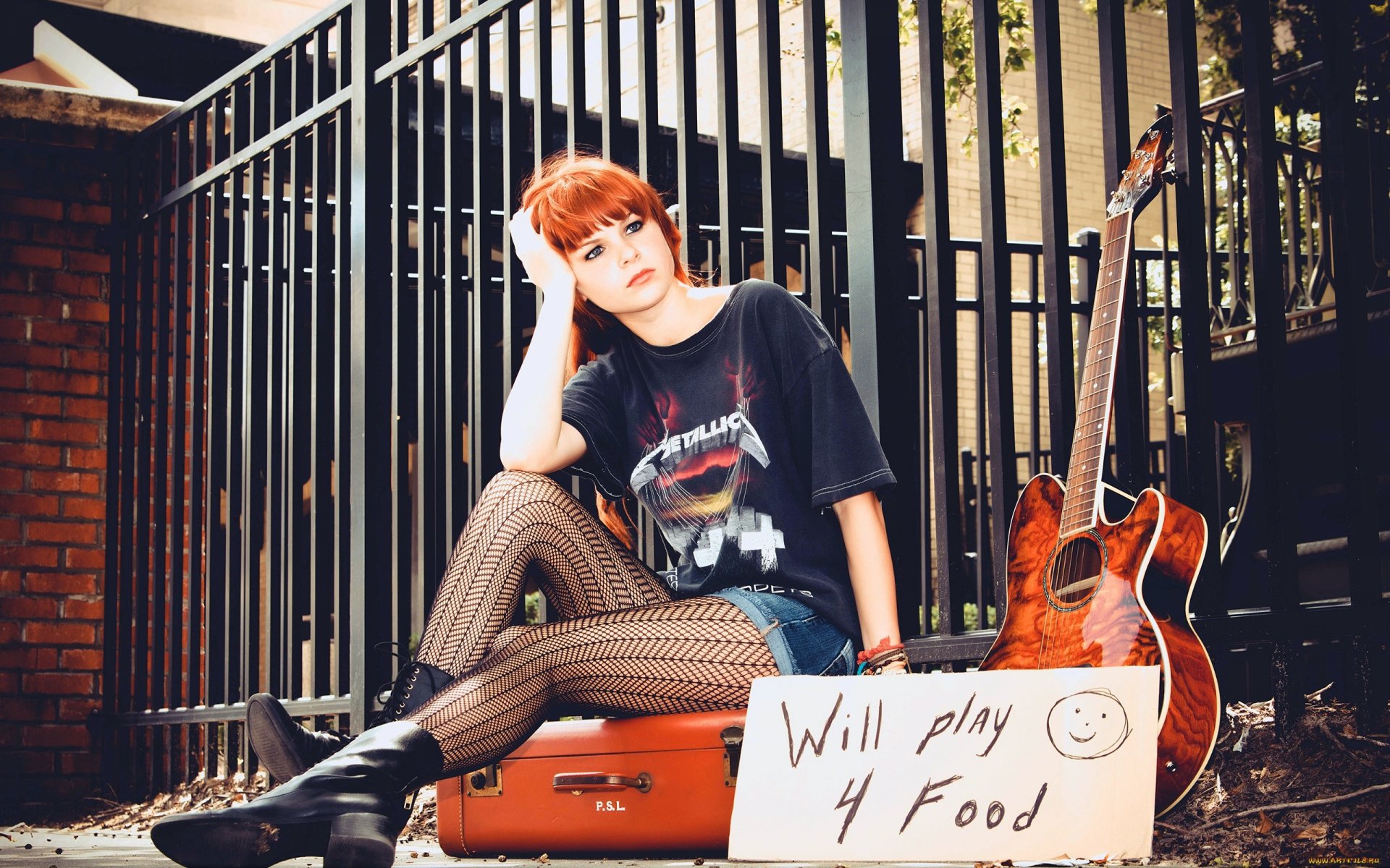A woman model sits thoughtfully with a guitar beside her, holding a sign that reads Will play 4 Food, set against a backdrop of a gated urban environment.
