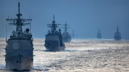 HD desktop wallpaper showing a military naval fleet sailing in formation on calm waters under a clear sky.