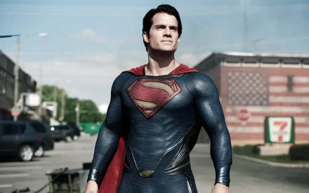 HD desktop wallpaper featuring Henry Cavill as Superman (Kal-El) from the movie Man of Steel, standing heroically in a small town street with a visible American flag in the background.