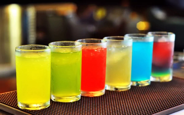 HD PC desktop wallpaper featuring a colorful row of six vibrant, translucent drinks on a bar mat, showcasing a visually appealing food and drink theme.