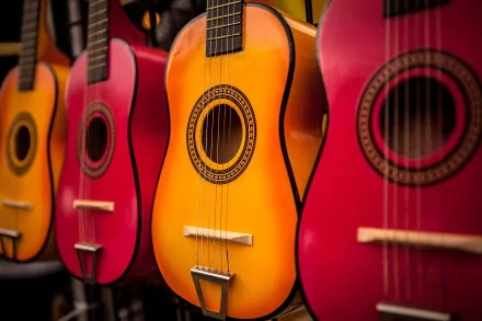 A vibrant display of acoustic guitars in shades of red and orange, capturing the essence of music. This HD desktop wallpaper enhances any background with its colorful charm.