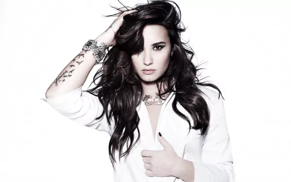 Brunette singer Demi Lovato poses confidently in a striking white dress, showcasing her style and talent. This HD image serves as an inspiring desktop wallpaper.