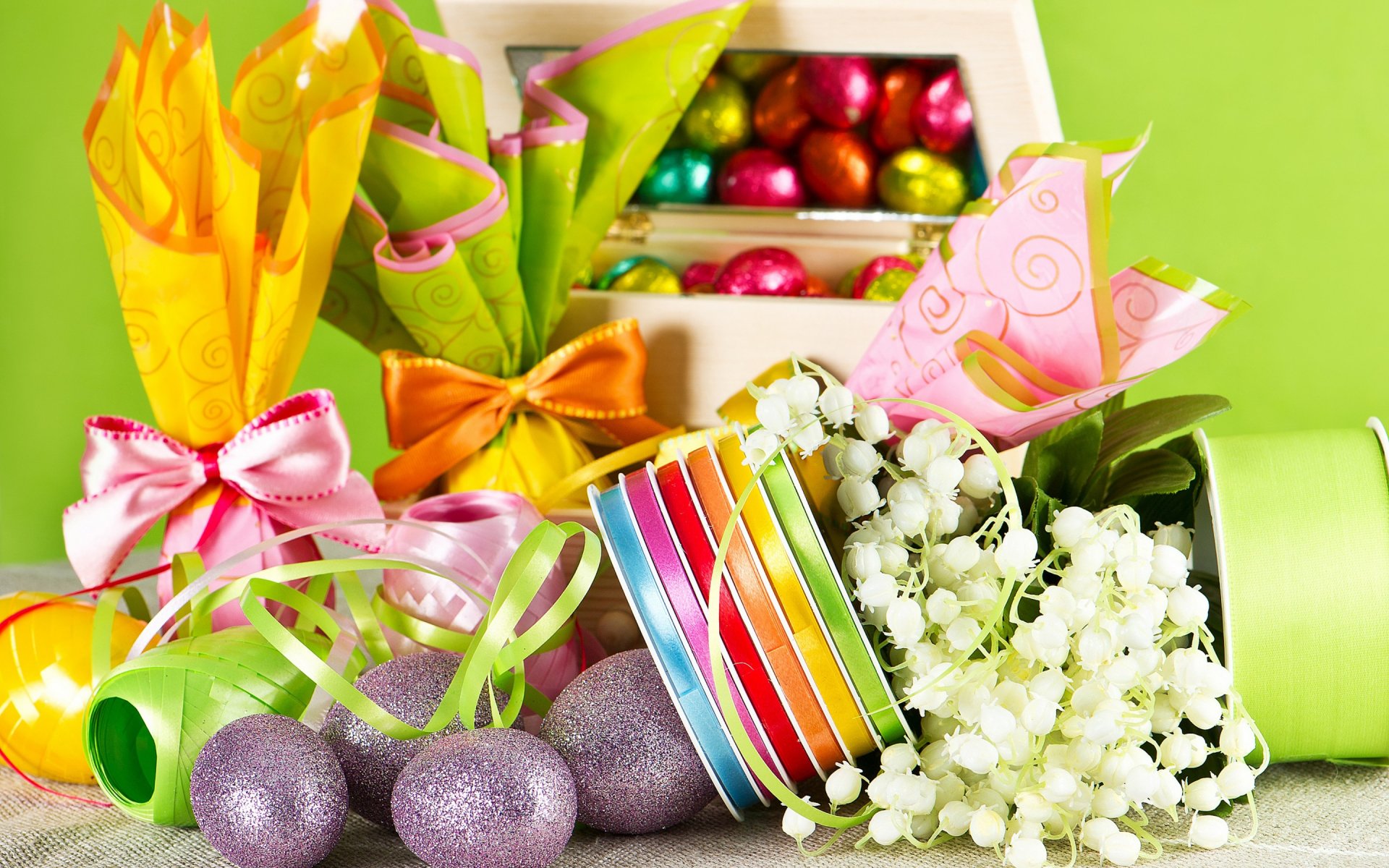 Colorful Easter-themed decorations featuring vibrant gift wraps, chocolate eggs, and pastel flowers, creating a festive and cheerful holiday atmosphere. HD desktop wallpaper for Easter.