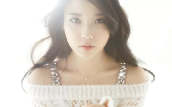 A high-definition desktop wallpaper featuring an Asian woman with long flowing hair, wearing a knitted off-shoulder top. She gazes softly towards the camera, surrounded by a soft, glowing light.