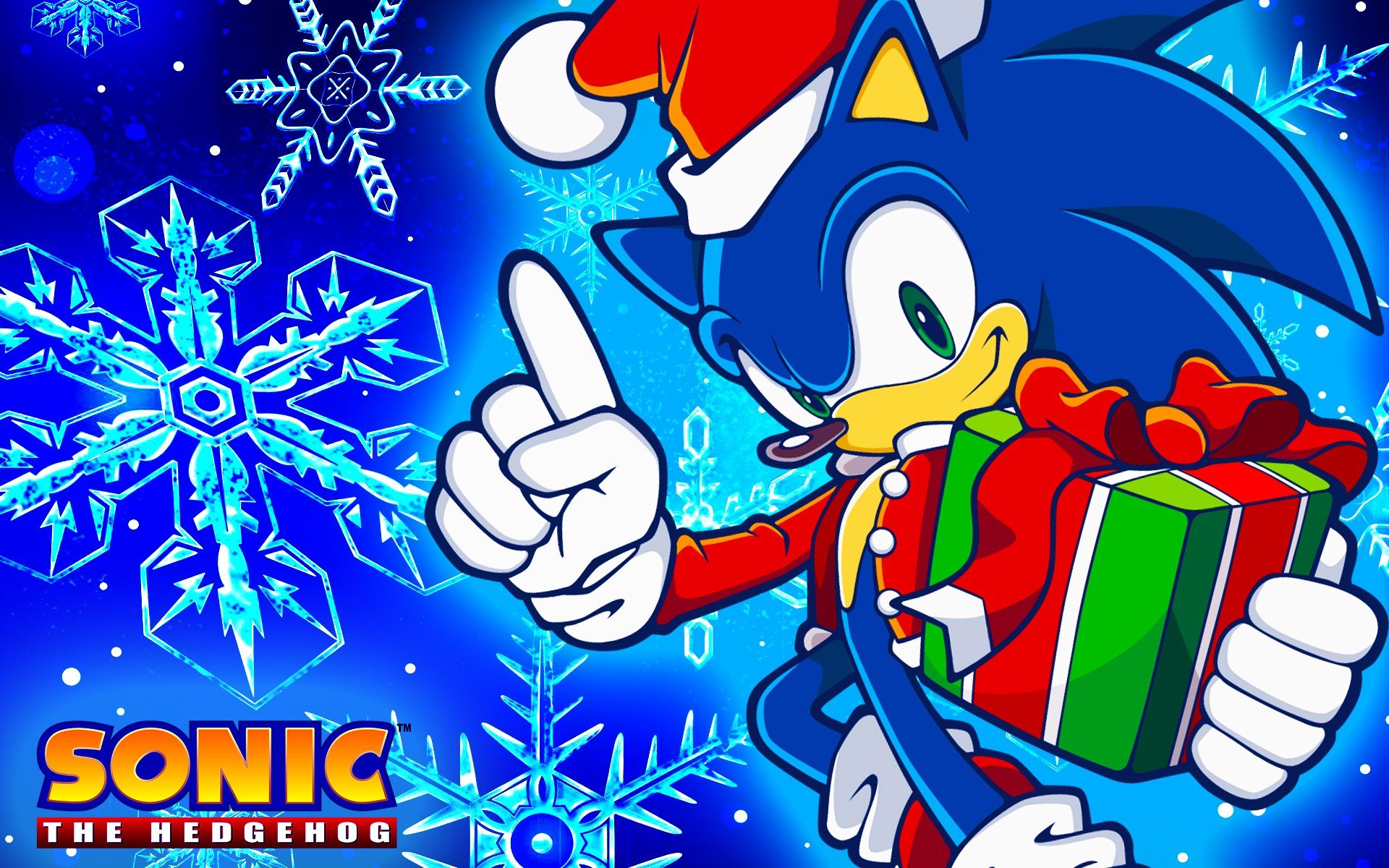 HD PC desktop wallpaper featuring Sonic the Hedgehog in a Santa hat holding a wrapped gift, set against a vibrant blue background with large snowflakes.