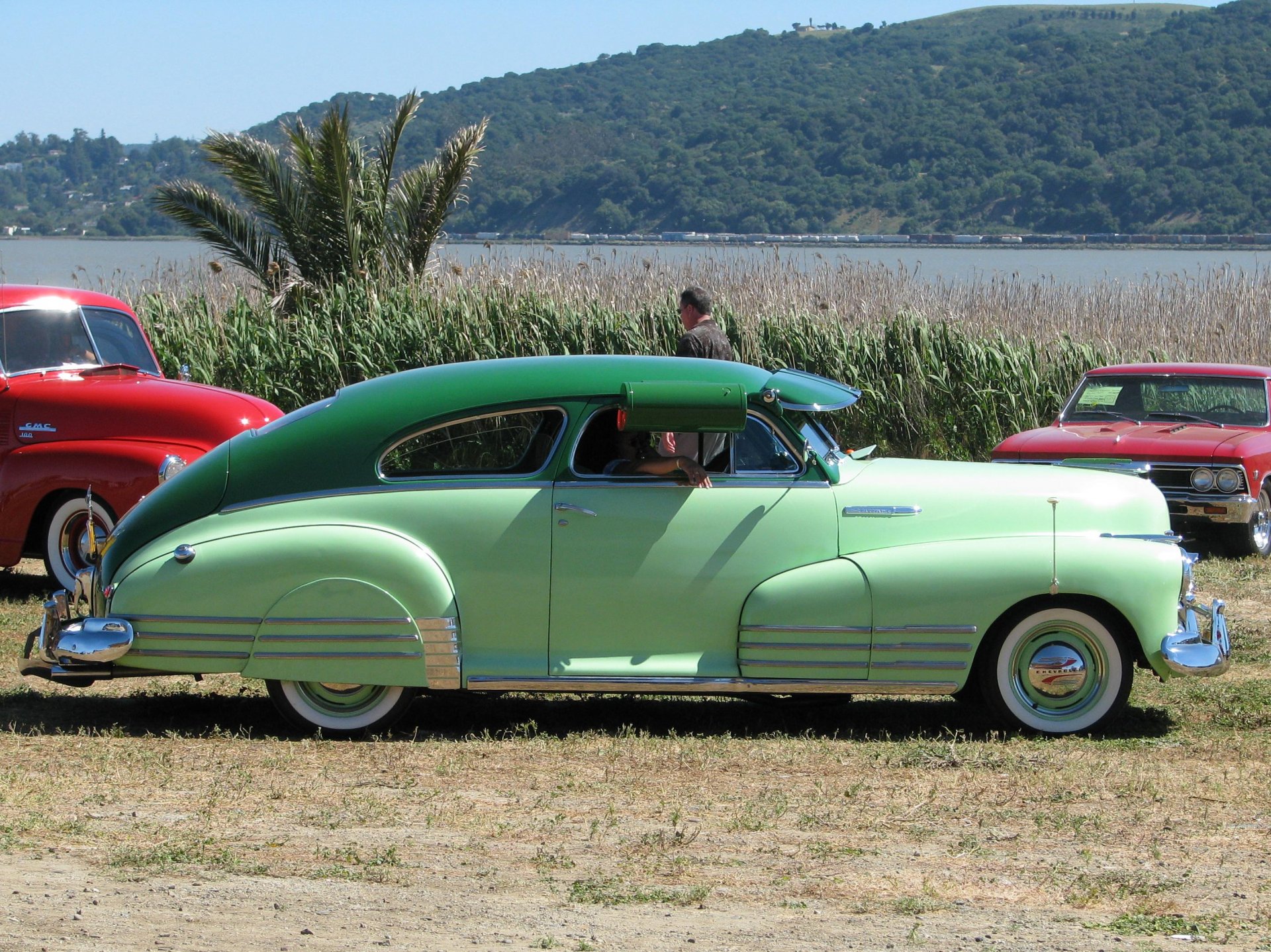 HD desktop wallpaper featuring a green 1948 Chevrolet Fleetline parked outdoors with natural scenery in the background, showcasing classic vehicle design.