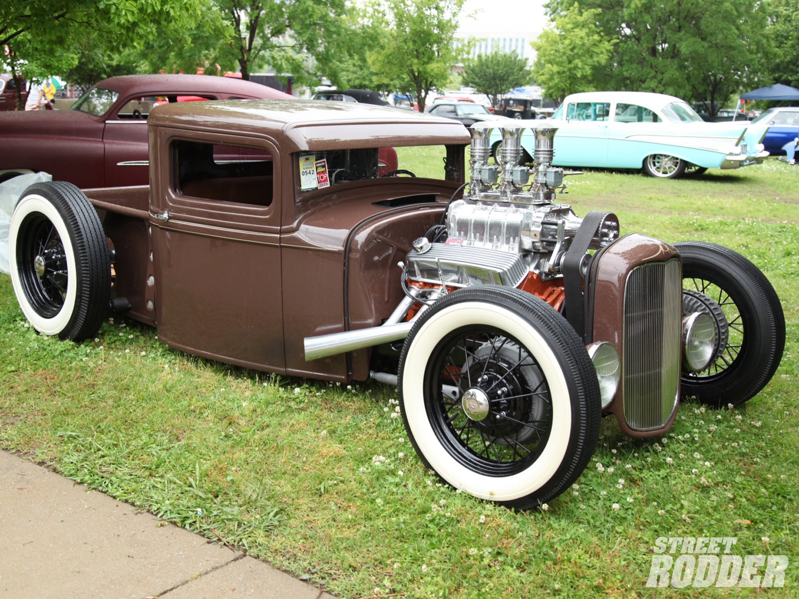 A classic truck with a unique design, featuring a polished engine and whitewall tires, set against a green backdrop. This high-definition image serves as an eye-catching desktop wallpaper.