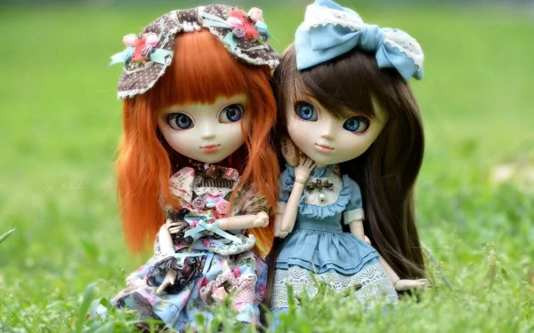 Two intricately designed dolls with vibrant hair and stylish outfits sit together on lush green grass, creating a charming and whimsical scene for a high-definition desktop wallpaper.