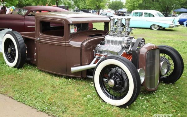 A classic truck with a unique design, featuring a polished engine and whitewall tires, set against a green backdrop. This high-definition image serves as an eye-catching desktop wallpaper.