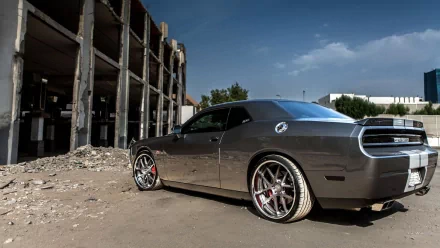 HD PC desktop wallpaper of a gray Dodge Challenger SRT8 vehicle parked beside a crumbling industrial building under a bright blue sky