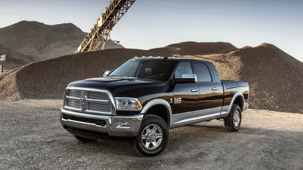 HD PC desktop wallpaper of a black Dodge Ram 2500 truck parked on a gravel surface with industrial equipment and mountains in the background.