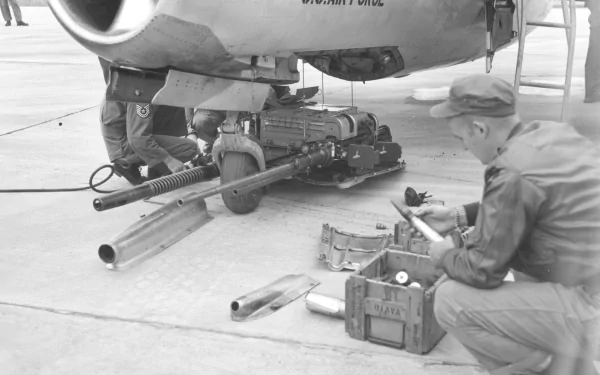 Black and white HD PC desktop wallpaper showing military personnel servicing aircraft weaponry on the ground.