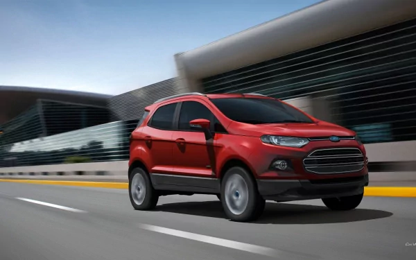 Red Ford EcoSport vehicle — compact SUV driving on an urban road, dynamic HD PC desktop wallpaper background.
