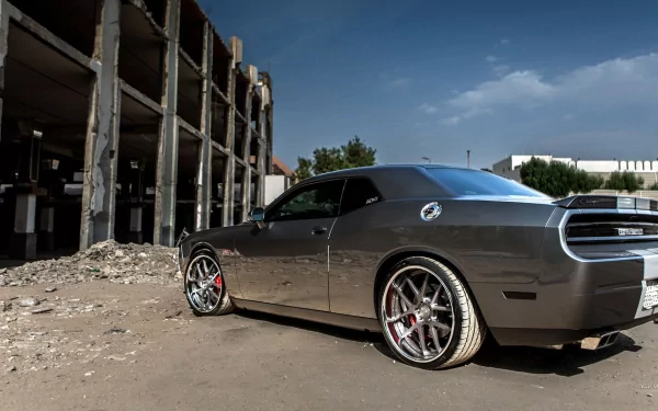 HD PC desktop wallpaper of a gray Dodge Challenger SRT8 vehicle parked beside a crumbling industrial building under a bright blue sky